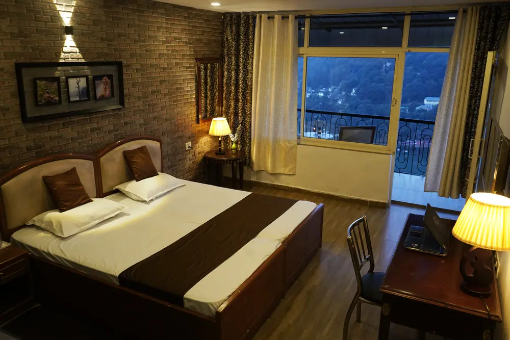 Lake View Super Deluxe Room with a double bed, brick feature wall and a balcony window