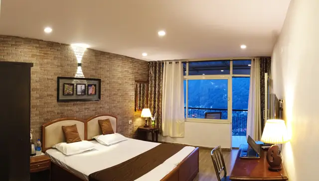 Lake view room at dusk with a private balcony and the Nainital hills outside