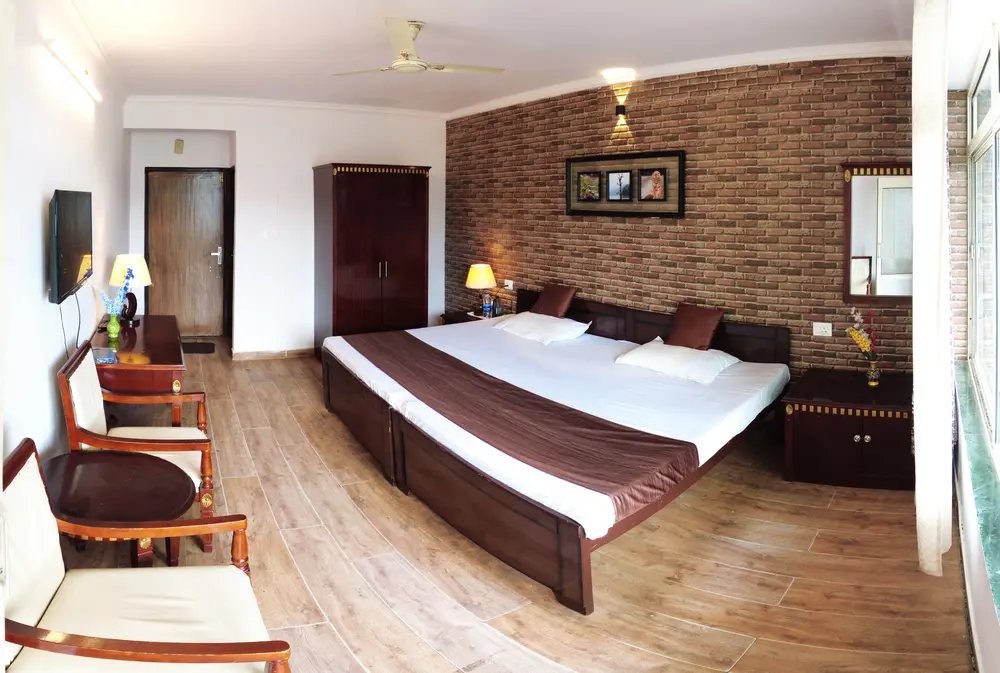 Wide view of a lake view room with bed, wooden seating and a large window