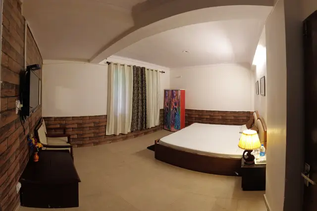 Standard Room with a double bed, television and brick-panelled wall