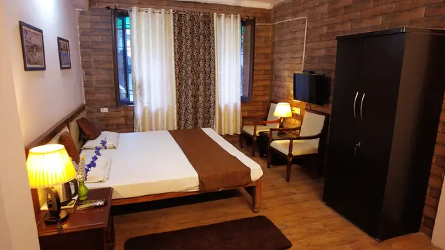 Standard Room with a double bed, cushioned chairs, wardrobe and lamp