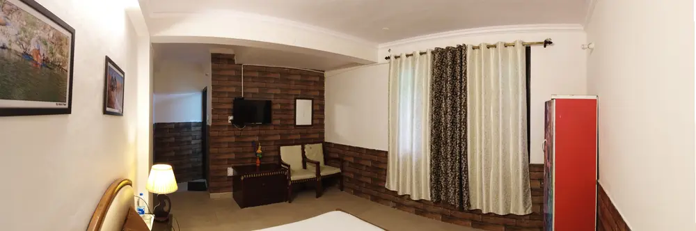 Wide view of a Standard Room with bed, television and curtains
